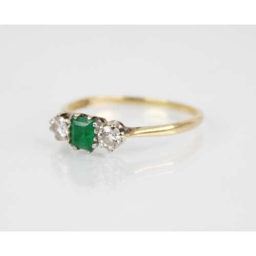 125 - An emerald and diamond three stone ring, the central rectangular step cut emerald measuring 4.5mm x ... 