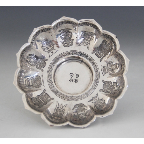 27 - A Chinese silver coloured saucer, of lobed circular form with shaped border, raised on tapered foot,... 