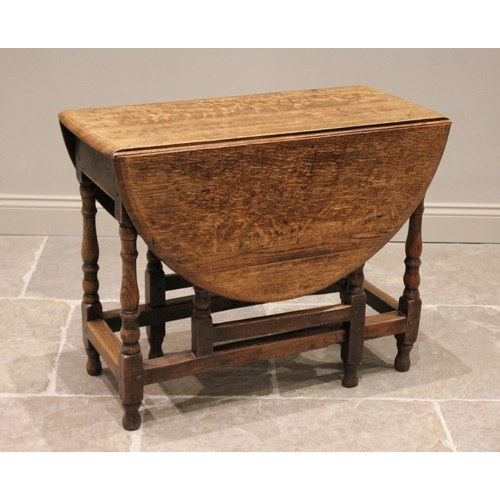 582 - An 18th century oak gateleg table, the oval drop leaf top raised upon baluster and bobbin turned sup... 