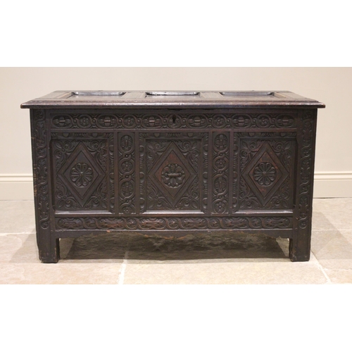 584 - A late 17th century/early 18th century carved oak coffer, the three panel cover opening to a fitted ... 