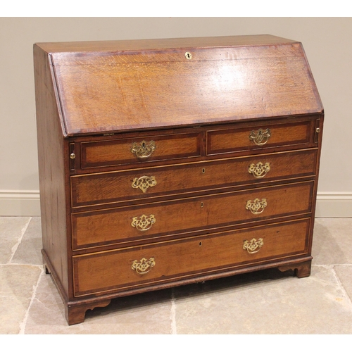 600 - A George III oak and mahogany cross banded bureau, the fall front opening to a compartmentalised int... 