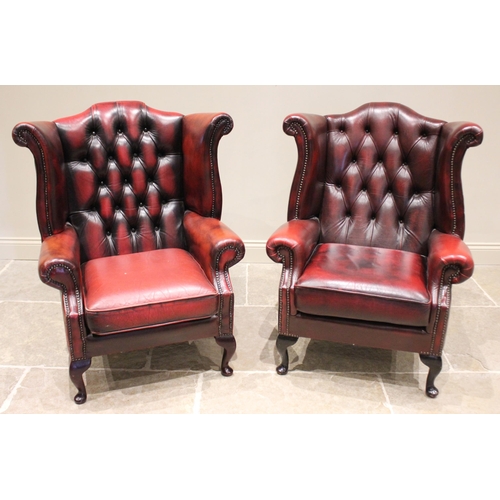 610 - A pair of George III style ox-blood red leather wing back armchairs, late 20th century, each with an... 