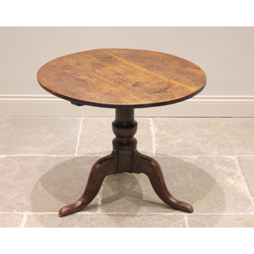 611 - A George III oak tripod table, the circular top raised upon a baluster column extending to three cab... 