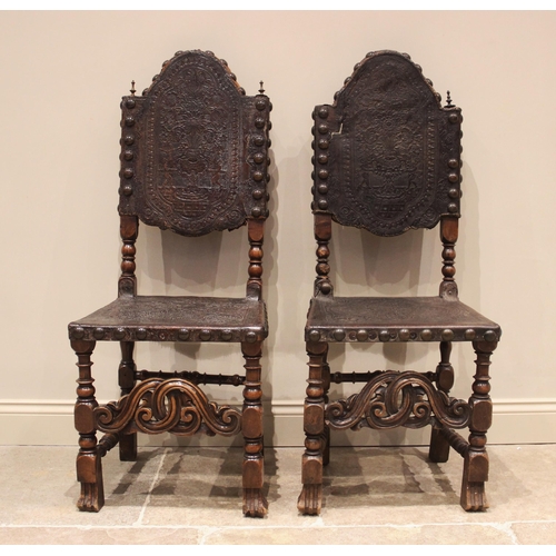 586 - A pair of 17th century and later walnut hall chairs, each with an arched and embossed leather back a... 