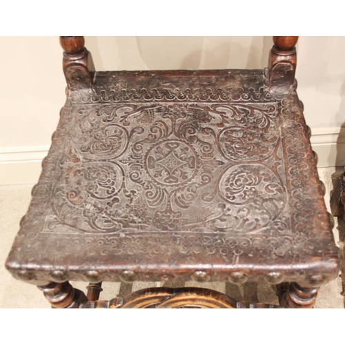 586 - A pair of 17th century and later walnut hall chairs, each with an arched and embossed leather back a... 