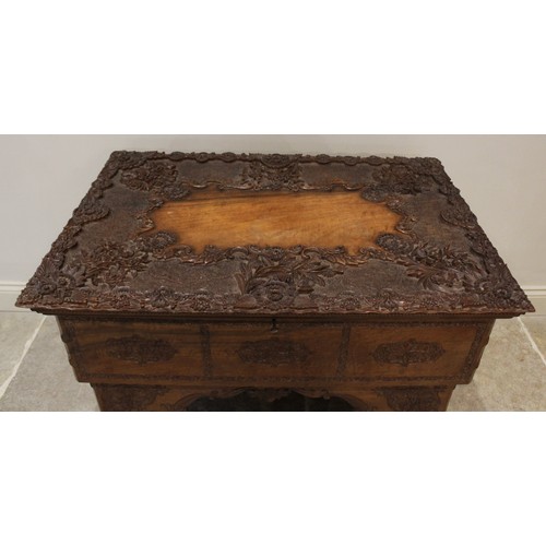 639 - An Anglo-Indian teak scholars table, the foliate relief carved hinged cover opening to reveal an arr... 