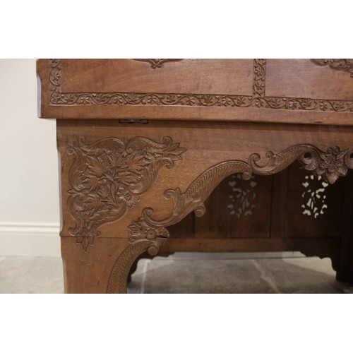 639 - An Anglo-Indian teak scholars table, the foliate relief carved hinged cover opening to reveal an arr... 