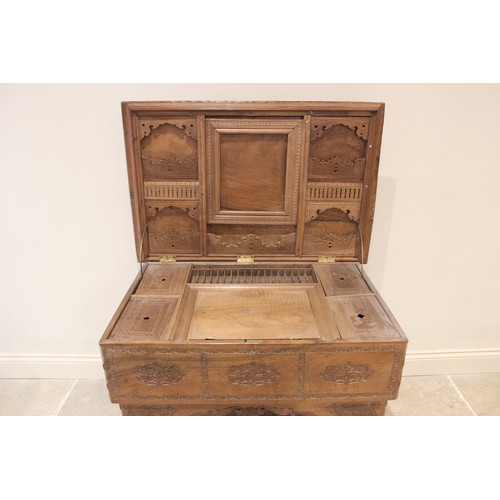 639 - An Anglo-Indian teak scholars table, the foliate relief carved hinged cover opening to reveal an arr... 