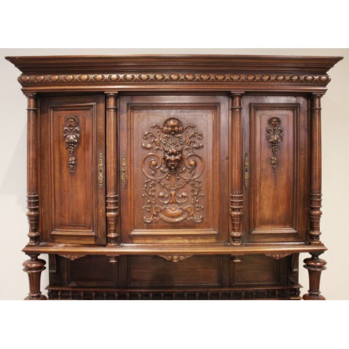 650 - A late 19th/early 20th century French walnut side cabinet, the upper section with three carved doors... 