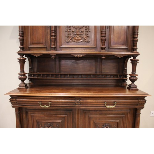 650 - A late 19th/early 20th century French walnut side cabinet, the upper section with three carved doors... 