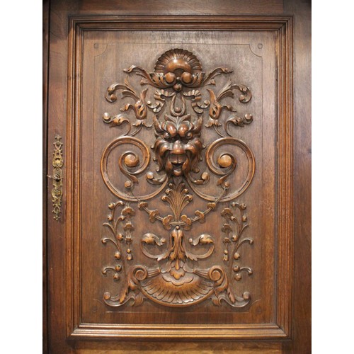 650 - A late 19th/early 20th century French walnut side cabinet, the upper section with three carved doors... 