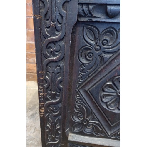 584 - A late 17th century/early 18th century carved oak coffer, the three panel cover opening to a fitted ... 