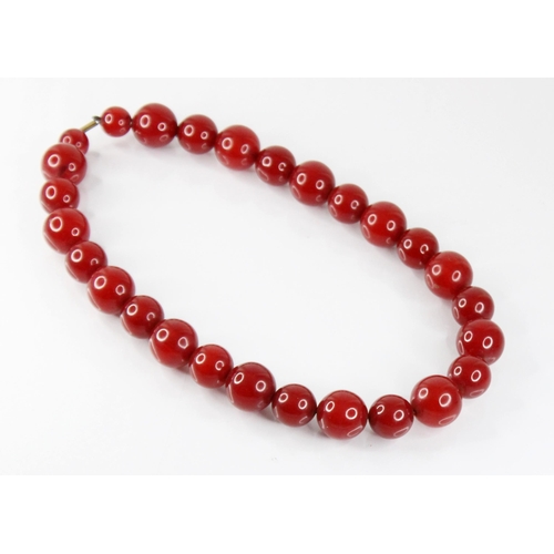 120 - A cherry amber bead necklace, comprising twenty-seven spherical cherry amber beads, smallest 13.5mm ... 