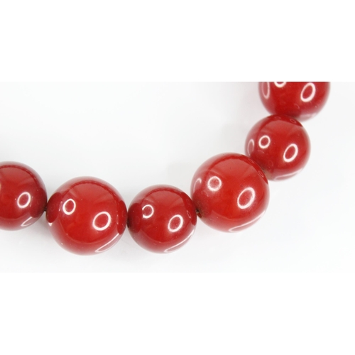 120 - A cherry amber bead necklace, comprising twenty-seven spherical cherry amber beads, smallest 13.5mm ... 