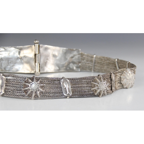 20 - An Indian silver coloured belt, designed as two tapered rectangular buckles, ornately embossed with ... 