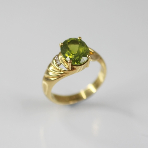 77 - A peridot and diamond 18ct gold ring, the central oval mixed cut peridot measuring 10mm x 8mm, claw ... 