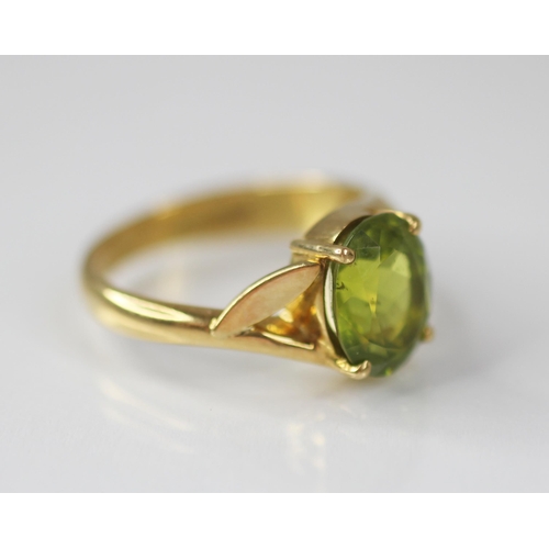 77 - A peridot and diamond 18ct gold ring, the central oval mixed cut peridot measuring 10mm x 8mm, claw ... 