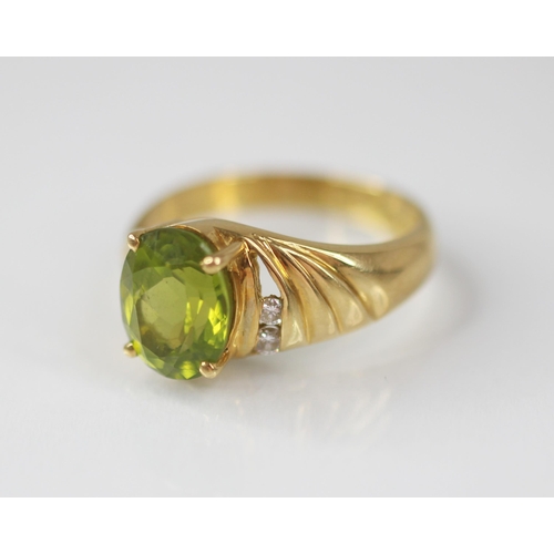 77 - A peridot and diamond 18ct gold ring, the central oval mixed cut peridot measuring 10mm x 8mm, claw ... 