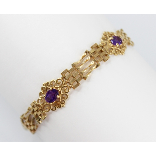 95 - A gold coloured amethyst set bracelet, the gate-link bracelet interspersed by three pierced scrollin... 