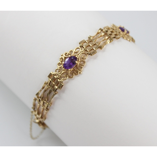 95 - A gold coloured amethyst set bracelet, the gate-link bracelet interspersed by three pierced scrollin... 