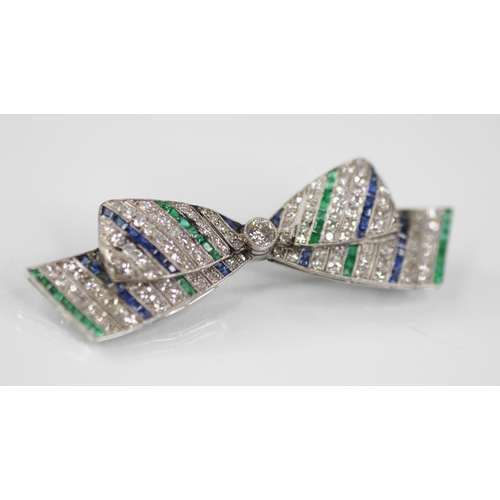 97 - An Art Deco diamond, sapphire and emerald bow brooch, the central round old cut diamond weighing app... 