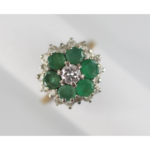 98 - An emerald and diamond floral cluster ring, the central round brilliant cut diamond with a 0.35 cara... 