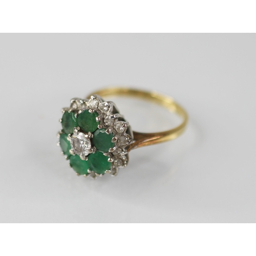 98 - An emerald and diamond floral cluster ring, the central round brilliant cut diamond with a 0.35 cara... 