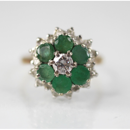 98 - An emerald and diamond floral cluster ring, the central round brilliant cut diamond with a 0.35 cara... 