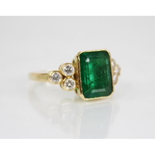 121 - An emerald and diamond 18ct gold ring, the central rectangular step cut emerald with canted corners ... 