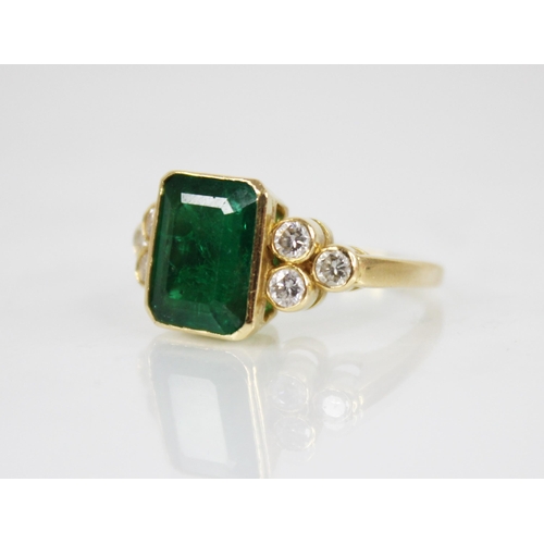 121 - An emerald and diamond 18ct gold ring, the central rectangular step cut emerald with canted corners ... 