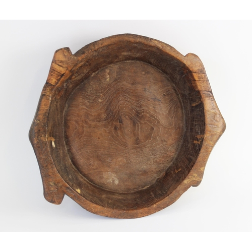 182 - A hand carved elm bowl, 19th century, of shallow circular flat bottomed form with integrated twin ha... 