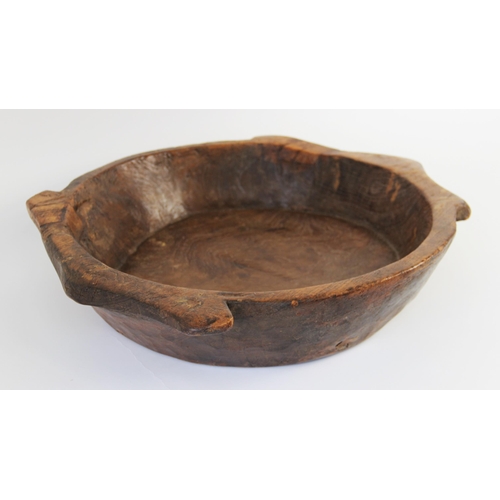 182 - A hand carved elm bowl, 19th century, of shallow circular flat bottomed form with integrated twin ha... 