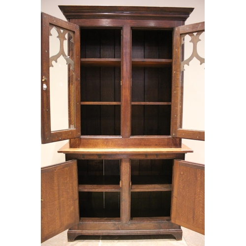 793 - A Victorian oak Gothic library bookcase, the moulded cornice above a pair of glazed doors applied wi... 