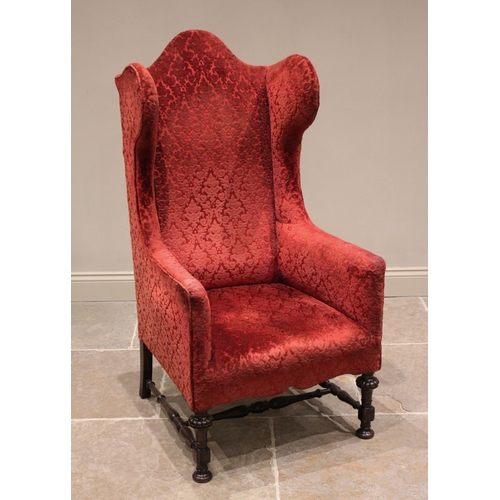 800 - A William and Mary style wing back armchair, early 20th century, in embossed red foliate fabric, the... 