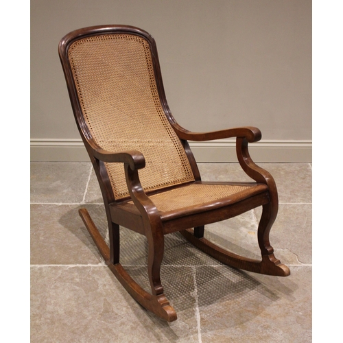 803 - A Victorian mahogany and rattan rocking chair, the arched cane back extending to down swept arms ove... 