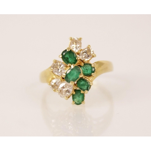 81 - An emerald and diamond 18ct gold cluster ring, the central tiered cluster comprising five oval cut e... 