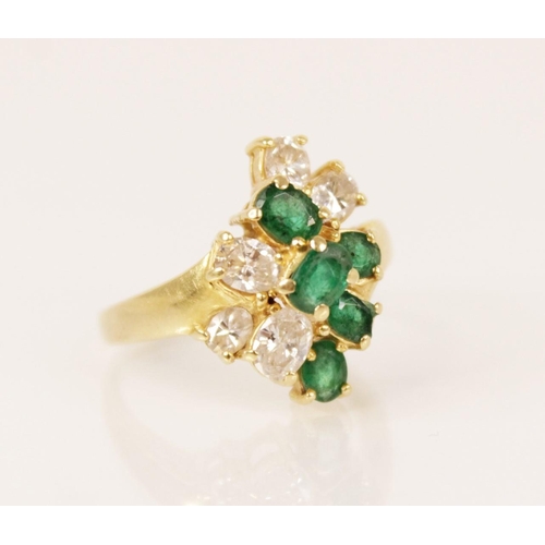 81 - An emerald and diamond 18ct gold cluster ring, the central tiered cluster comprising five oval cut e... 