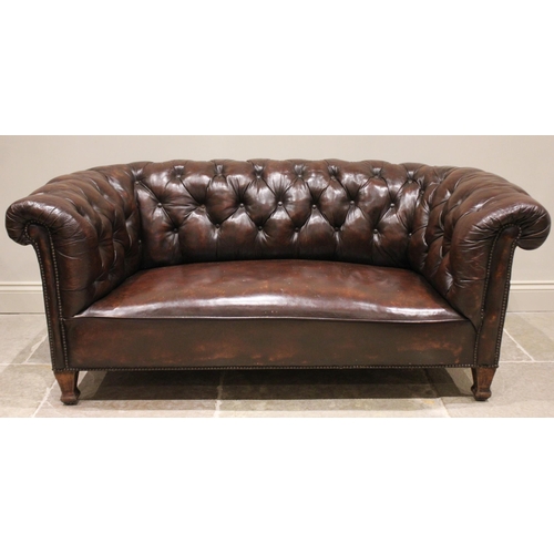 810 - An early 20th century oak framed Chesterfield sofa, with typical deep set button back and arms, appl... 