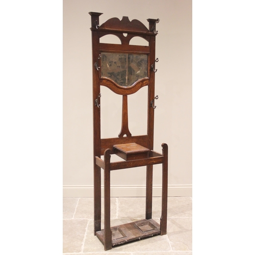 814 - An early 20th century oak Art Nouveau hall stand, the rail back with a shaped mirror over a hinged g... 