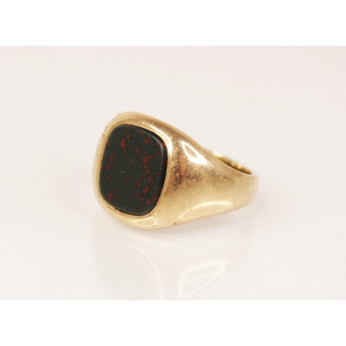 87 - A bloodstone set 9ct gold signet ring, the central rounded square matrix measuring 10.2mm x 9.6mm, s... 