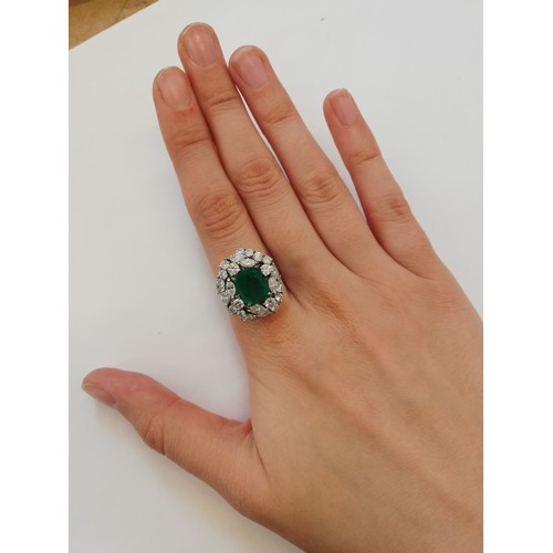 159 - An emerald and diamond ring, the central rectangular step cut emerald measuring 9.7mm x 8.0mm, set t... 