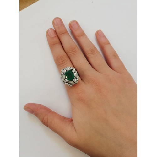 159 - An emerald and diamond ring, the central rectangular step cut emerald measuring 9.7mm x 8.0mm, set t... 