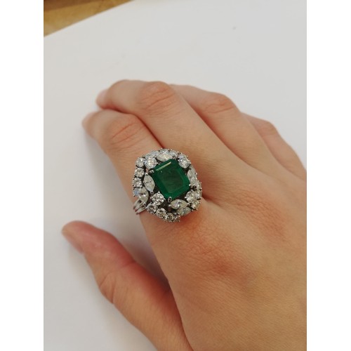 159 - An emerald and diamond ring, the central rectangular step cut emerald measuring 9.7mm x 8.0mm, set t... 