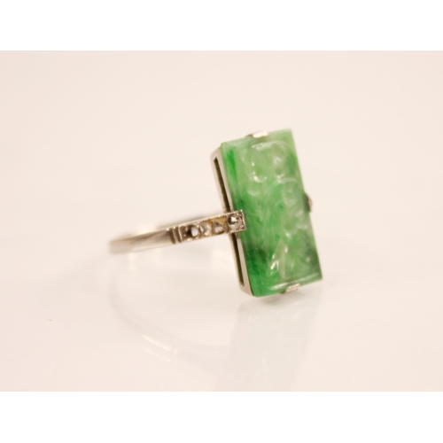 156 - An Art Deco jade and diamond ring, the central rectangular carved and pierced jade panel measuring 1... 