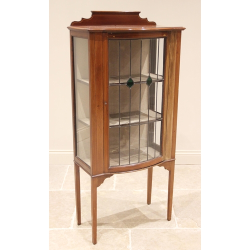 806 - An Edwardian mahogany display cabinet, with a shaped rear gallery above a bowfront leaded and colour... 