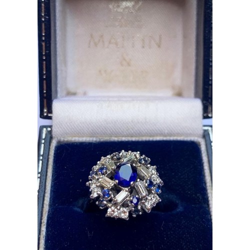 149 - A sapphire and diamond cluster ring, the central oval mixed cut sapphire measuring 6mm x 5mm, within... 