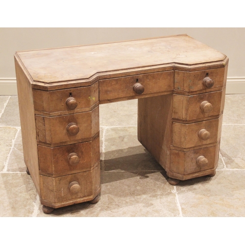 761 - An Art Deco pine kneehole desk, of inverted breakfront form with canted corners, the central frieze ... 