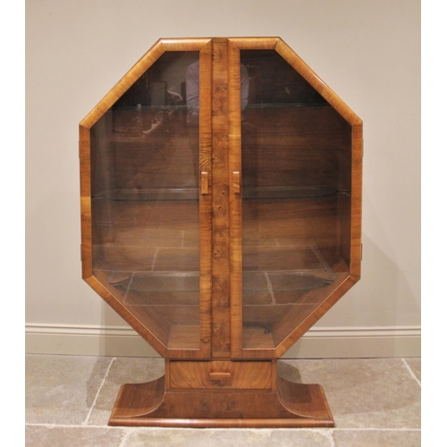 799 - A 1930's Art Deco octagonal walnut display cabinet, the pair of glazed doors opening to two glass sh... 