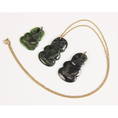 155 - Three New Zealand jade Tiki pendants, one with attached yellow metal chain, largest 4cm, smallest 3c... 