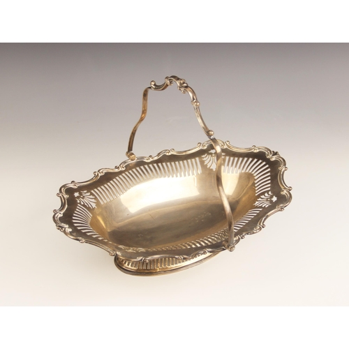 3 - A George V silver swing-handled dish, of oval form with scrolling shaped border and pierced detail, ... 